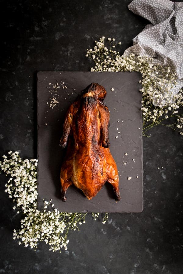 Whole roasted duck on slate board with baby's breath flowers