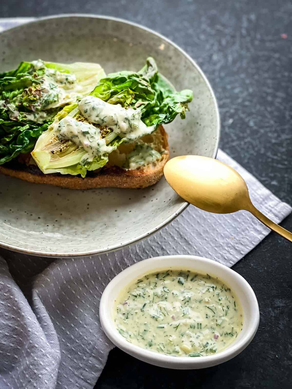 Grilled Little Gem Salad with Tahini Ranch Dressing on toast served in a grey bowl