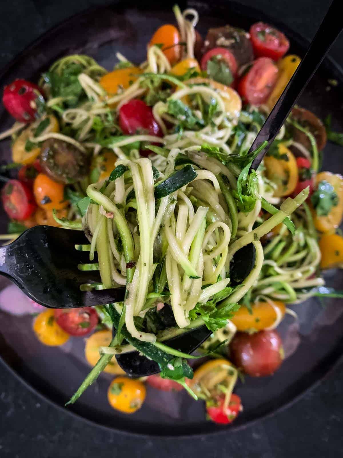 2 forks lifting a serve of Vegan Zucchini Noodle Salad with Pesto from the plate