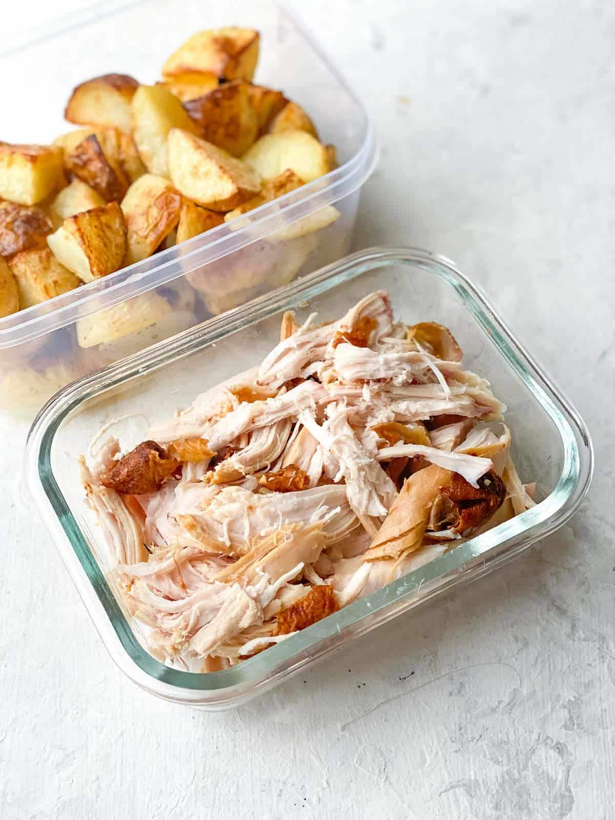 Leftover chicken and roast potatoes in takeaway containers