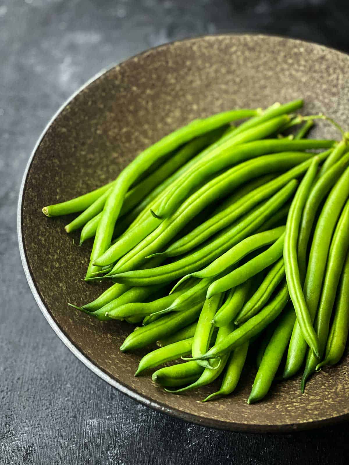 Fresh green beans on an earth coloured shallow bowl