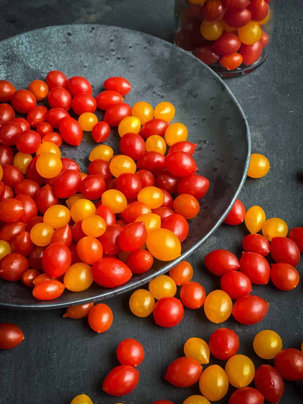 Red and orange Tomberry tomatoes on a grey side plate