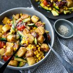 Pan Fried Gnocchi with Tomato, Corn and Zucchini in a grey bowl with serving cutlery and dotted linen