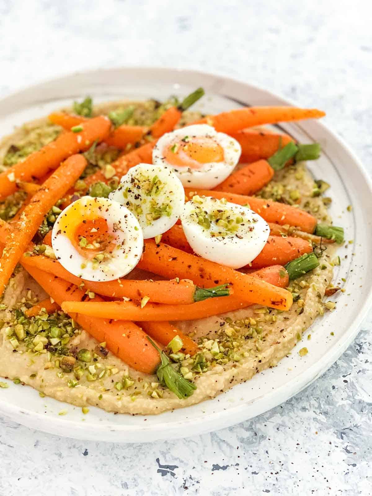 Salad of Dutch Carrots, Hummus and Soft-Boiled Eggs on a white marbled plate