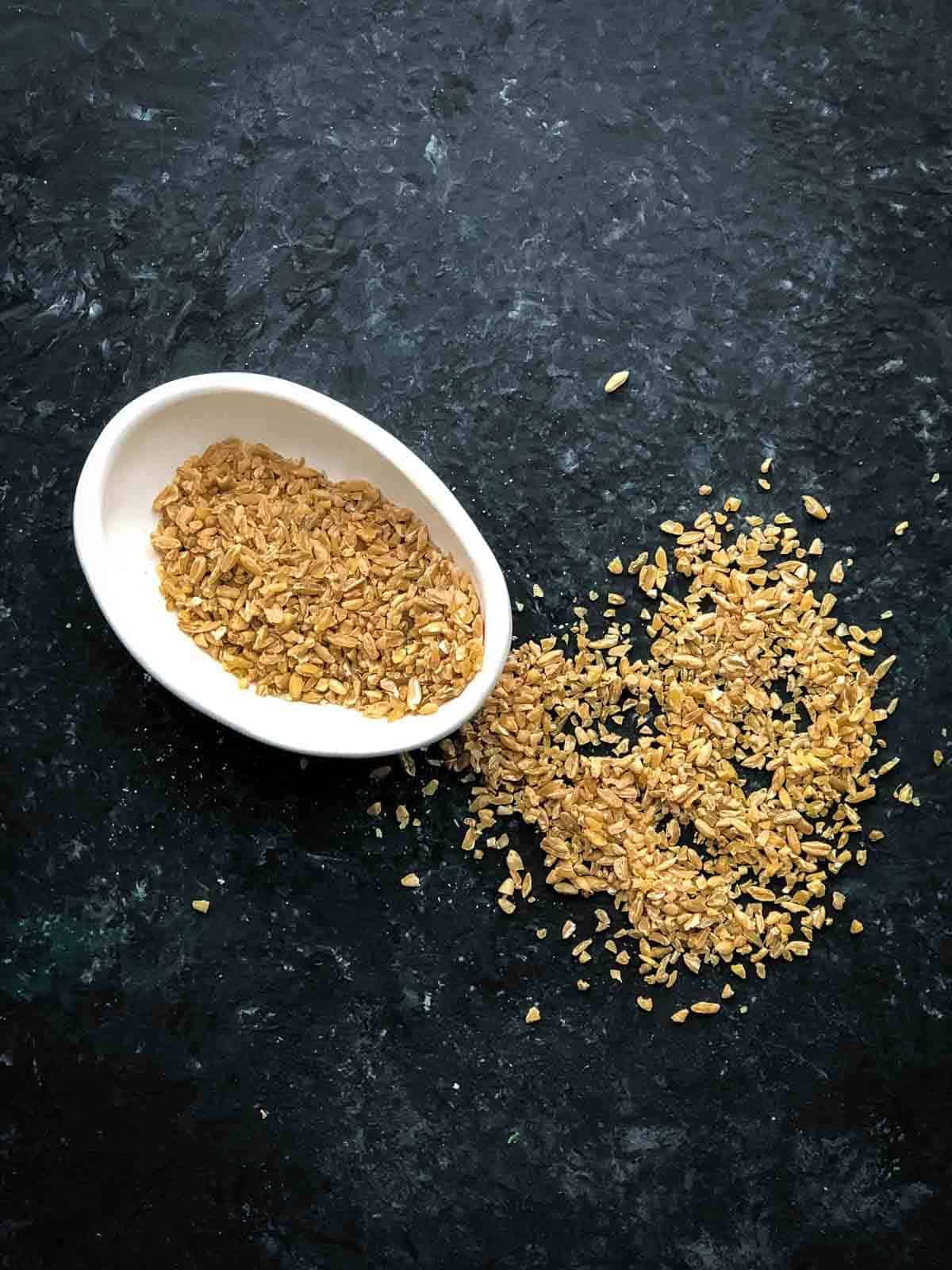 Uncooked freekeh in a small bowl and on a board
