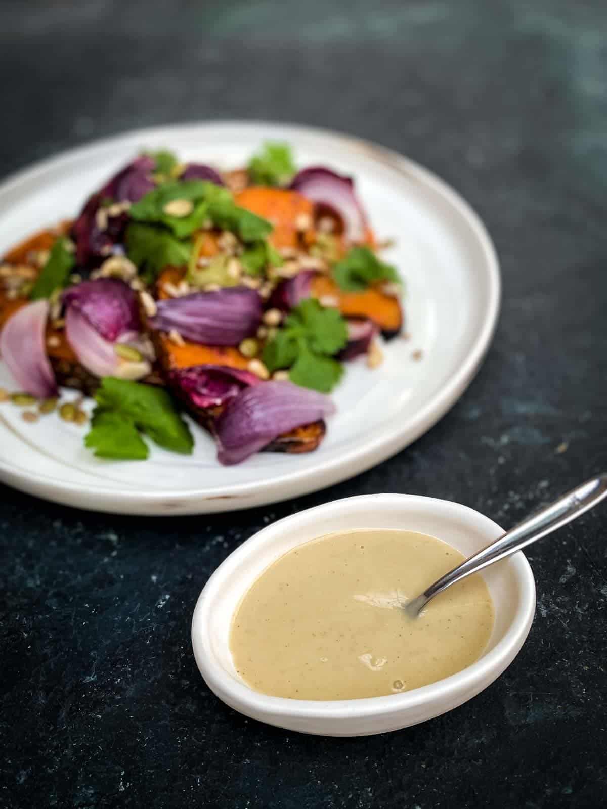 Tahini Miso Dressing in a small bowl with a fork served with Roasted Spiced Pumpkin Salad