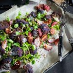 Roasted Radish Salad with Cauliflower ons a sheet pan with baking paper and black cutlery