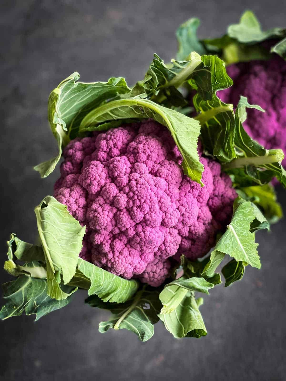 Whole purple cauliflower with green leaves