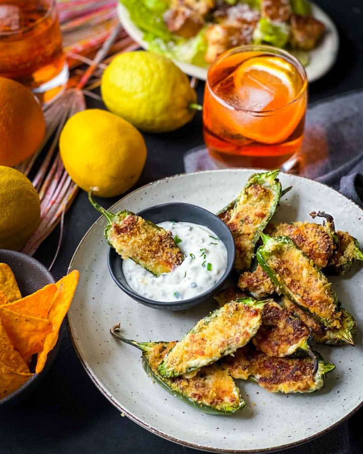 Dipping Air Fryer Jalapeno Poppers in sour cream dips served with Caesar salad, orange drinks and corn chips