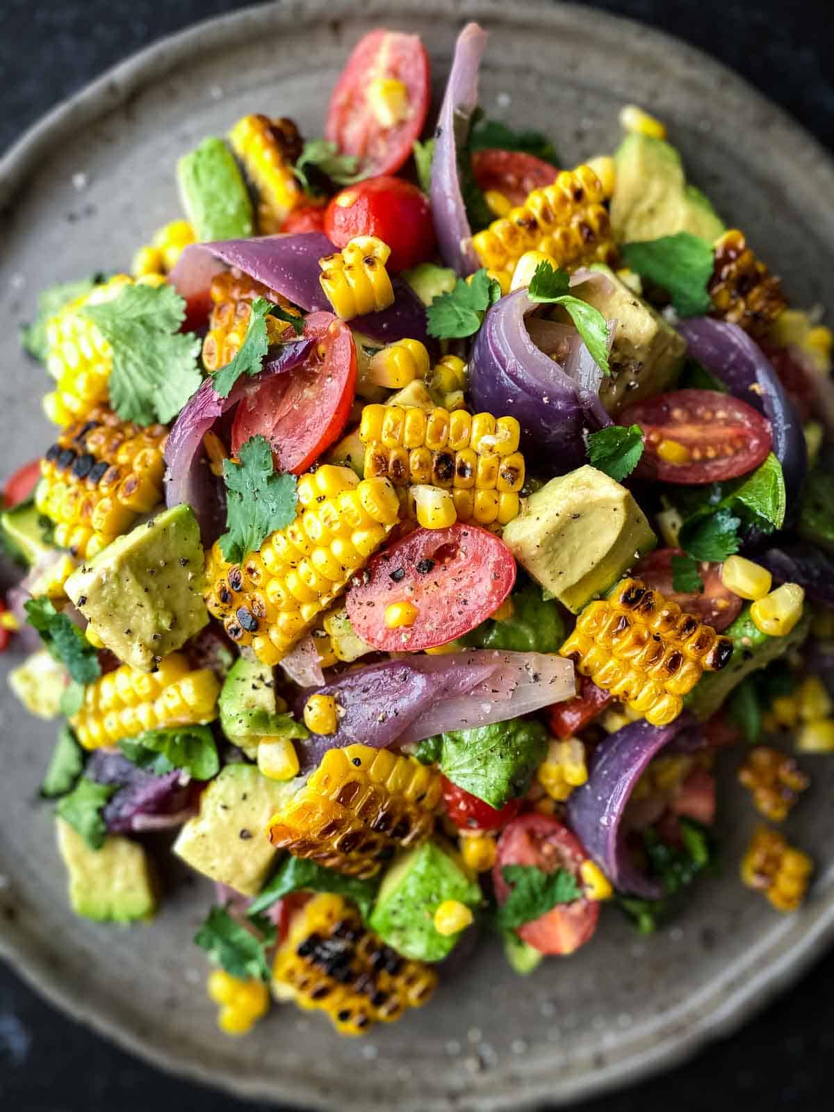 Charred Corn Avocado Salad with Roasted Red Onions on a grey plate