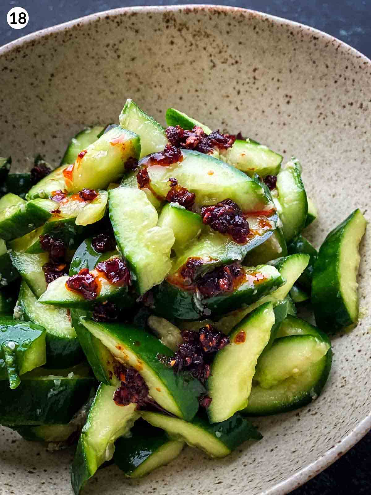 Smashed cucumber salad in a light brown speckled bowl topped with chilli oil