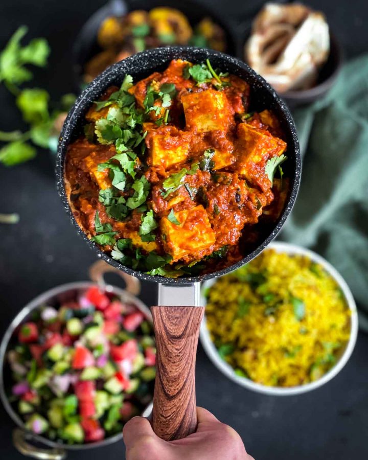 Paneer Butter Masala in a pot served with naan and turmeric rice
