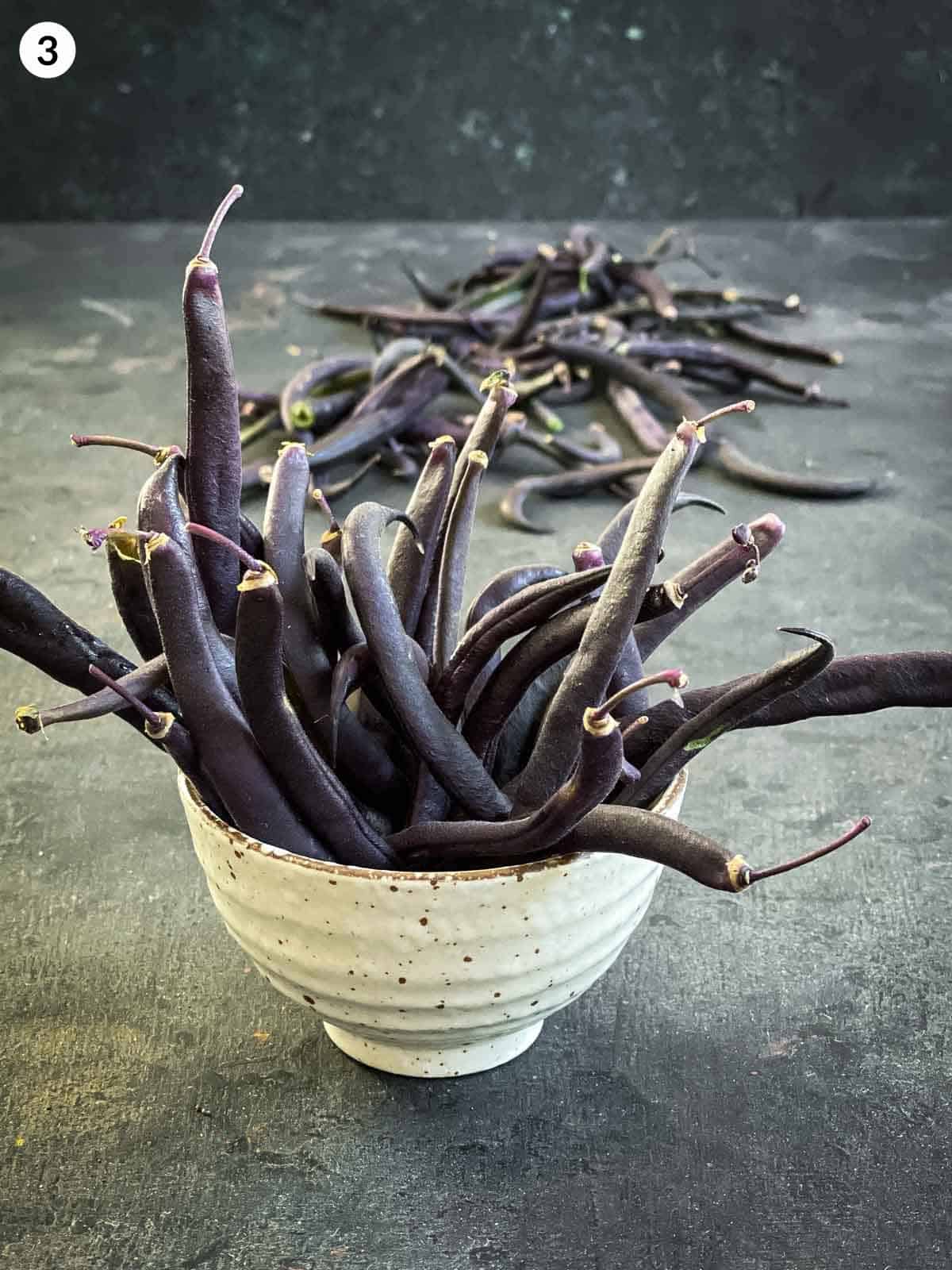 Fresh purple beans in a white bowl