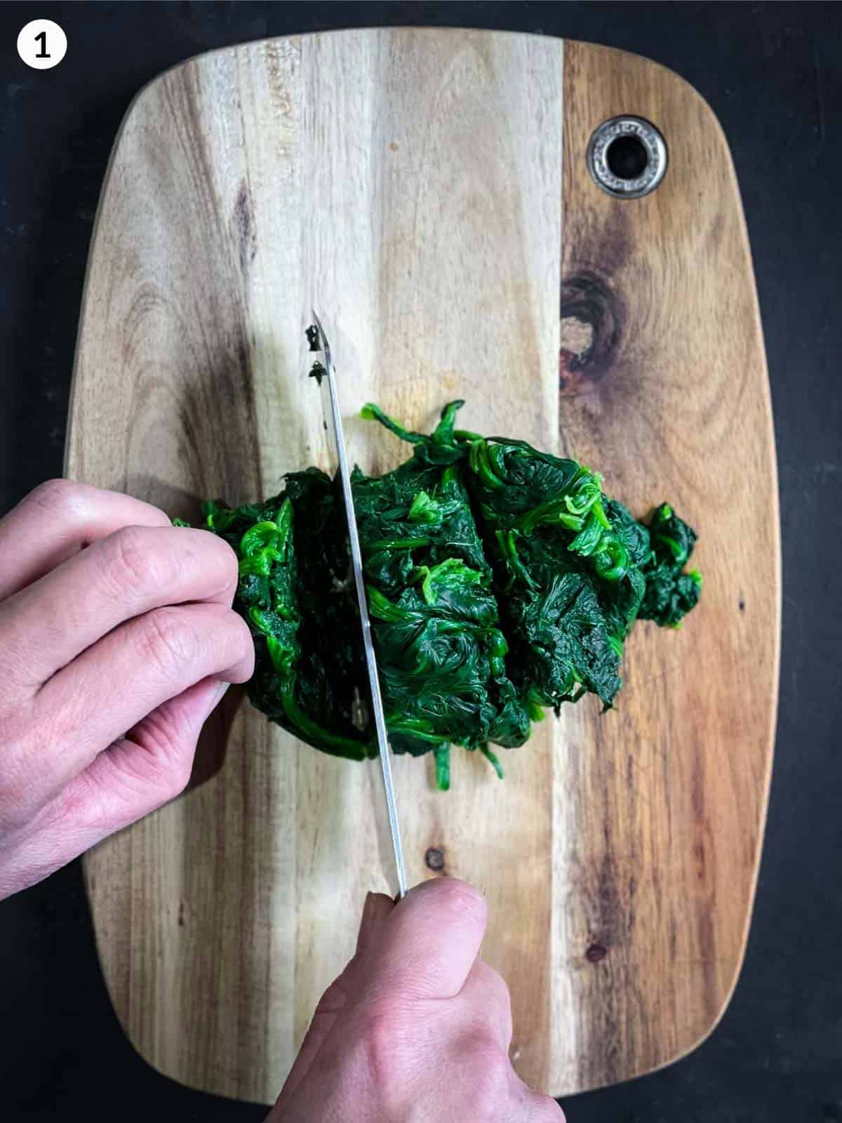 Chopping cooked Kkorean spinach with a knife on a wooden chopping board