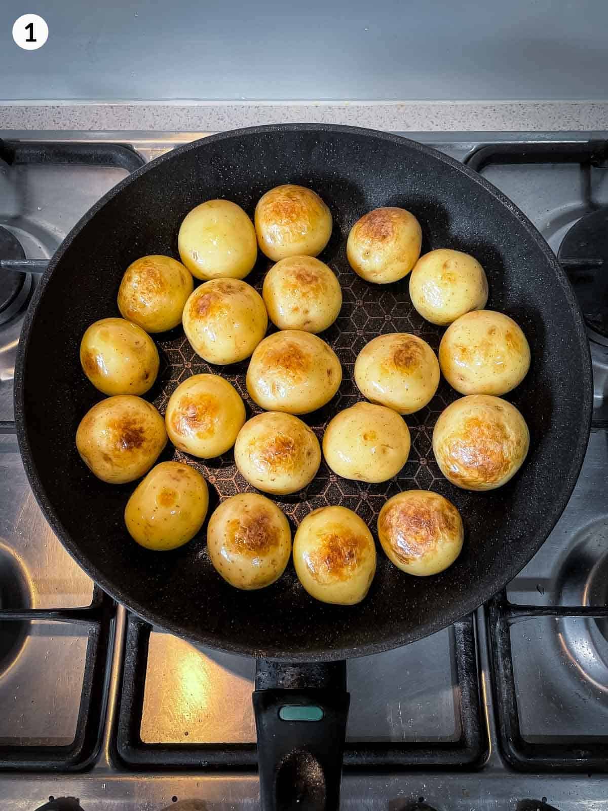 Pan frying whole baby potatoes in a fry pan on a stove top