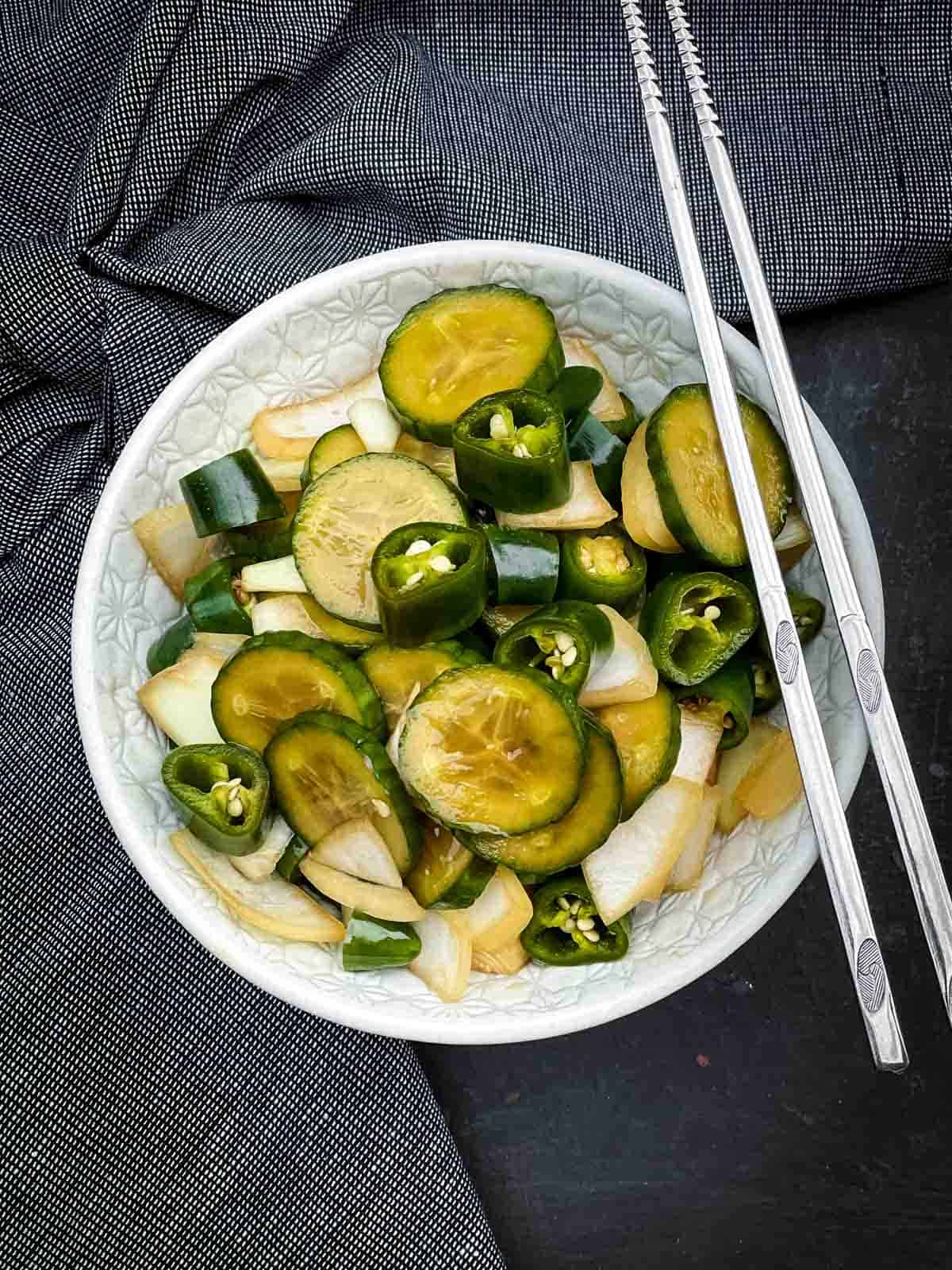 Korean Pickles in Soy Sauce - Jangajji in a white bowl with chopsticks and blue napkins