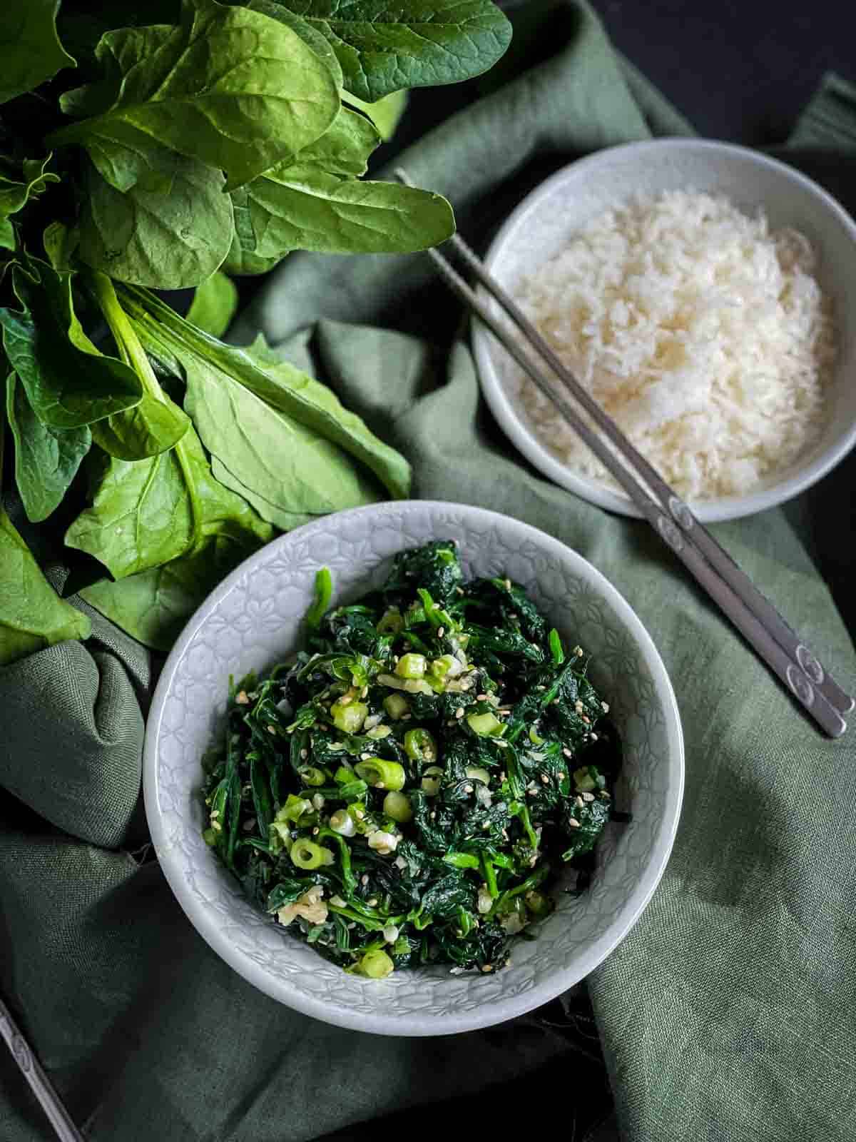 Korean Spinach Side Dish - Sigeumchi Namul served with rice on green tablecloth