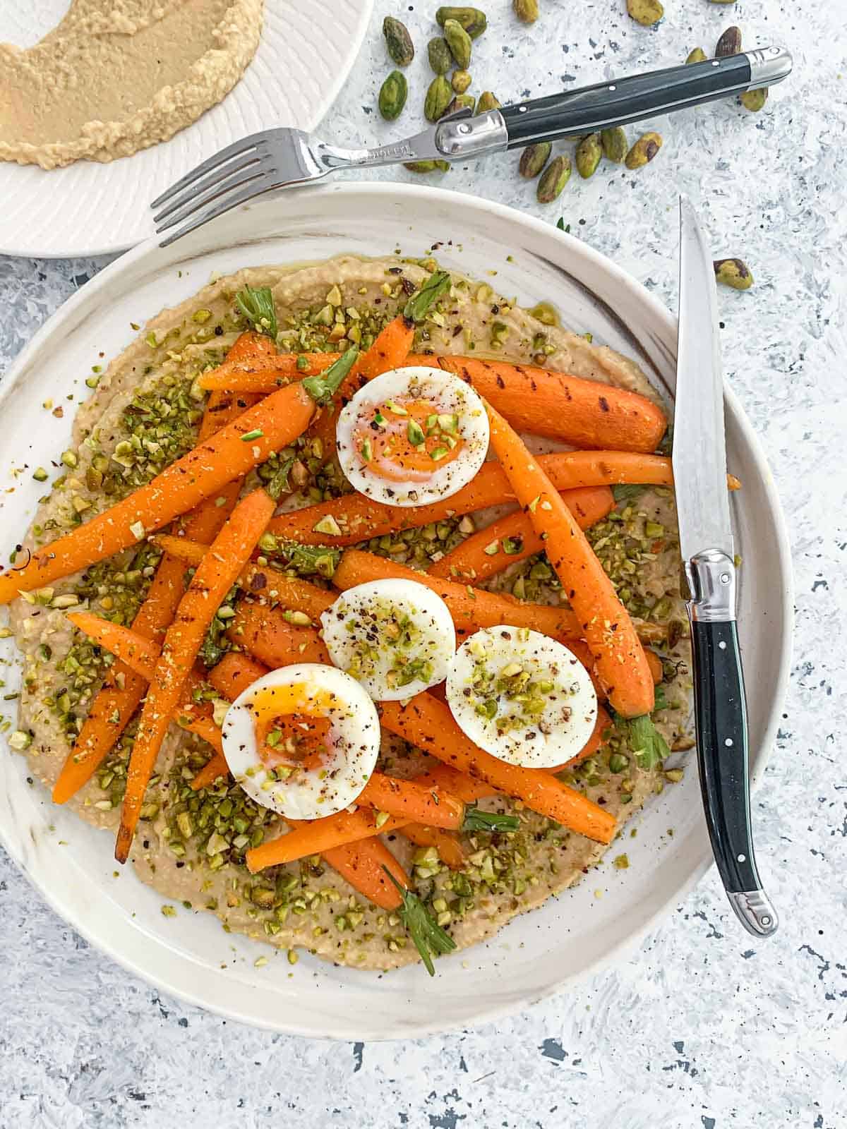 Enjoy the creaminess of this Dutch carrot salad without the use of any dairy. The combination of the hummus and the oozing soft-boiled eggs provide for a velvety alternative. Add in the crunch of the pistachios and you have a delectable side salad.