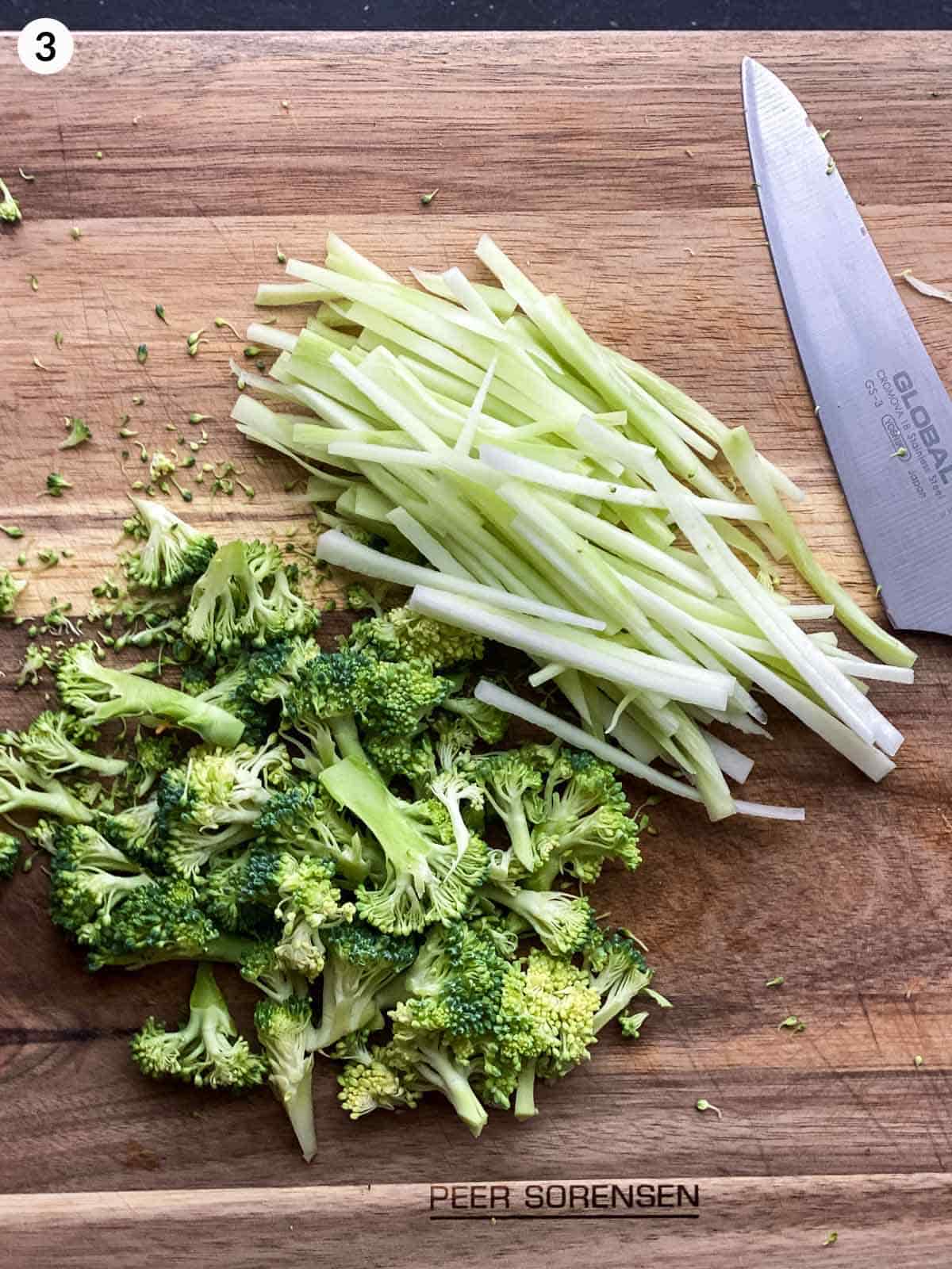 2 hands cutting broccoli and broccoli stems with a knife on a chopping board