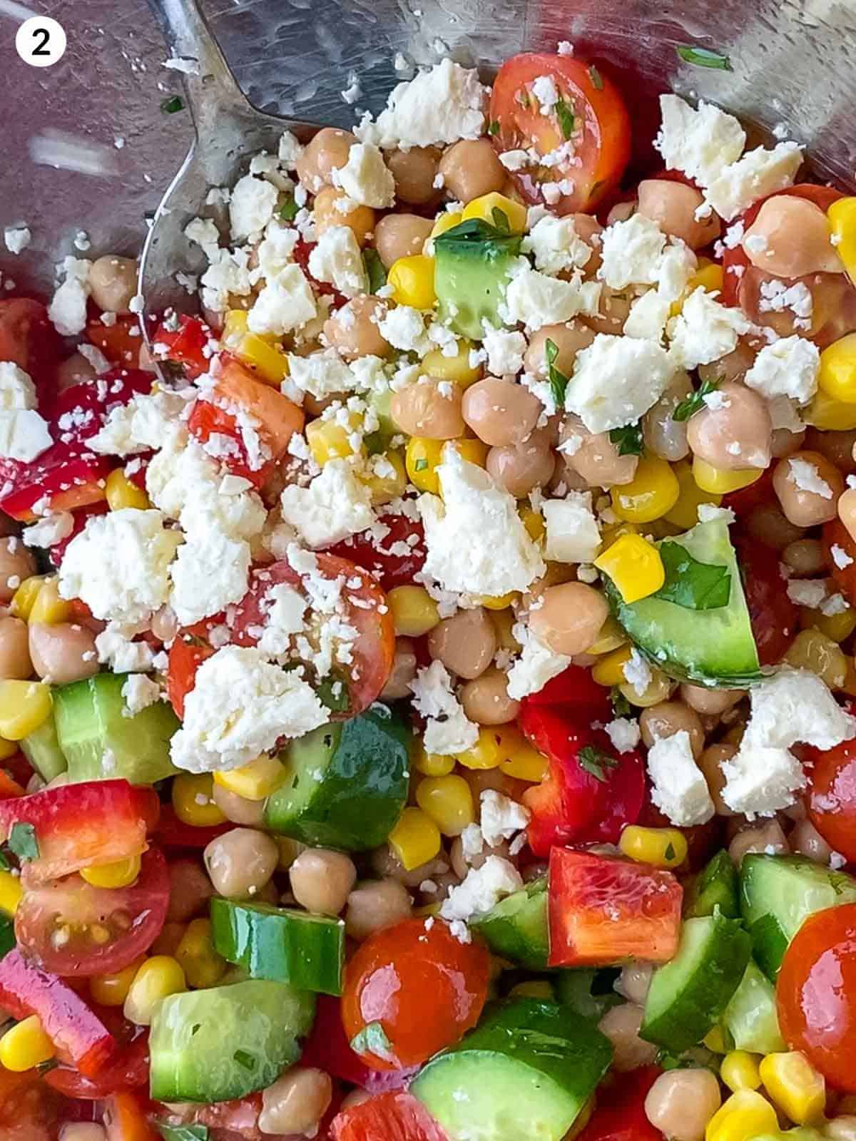 Mixing Chickpea Salad with Feta in a stainless steel bowl