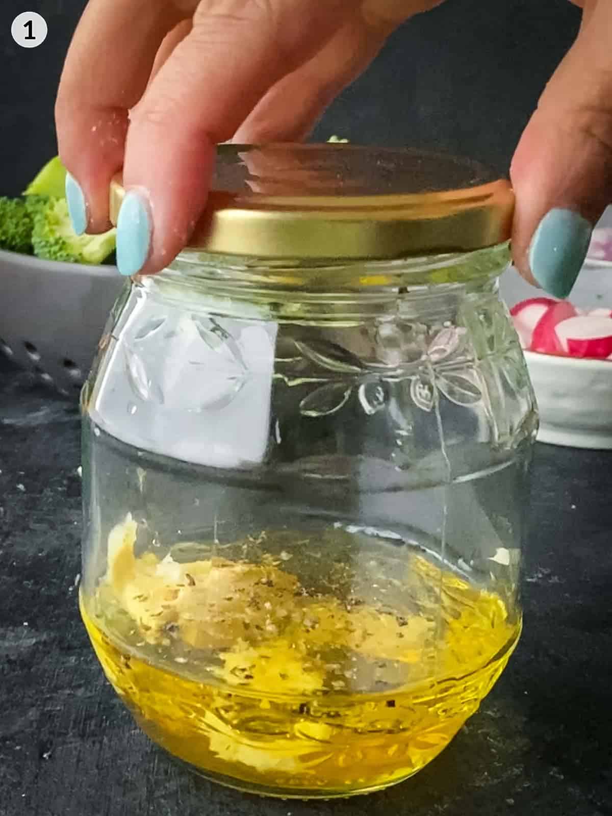 hand placing the lid on a jar of tangy mustard dressing