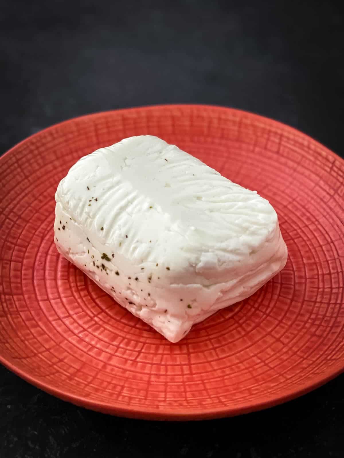 block of halloumi cheese on a red textured plate