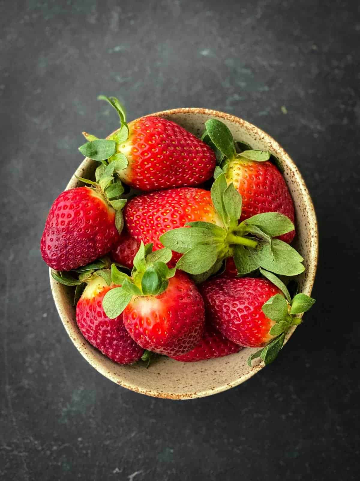 a bowl of strawberries with black background