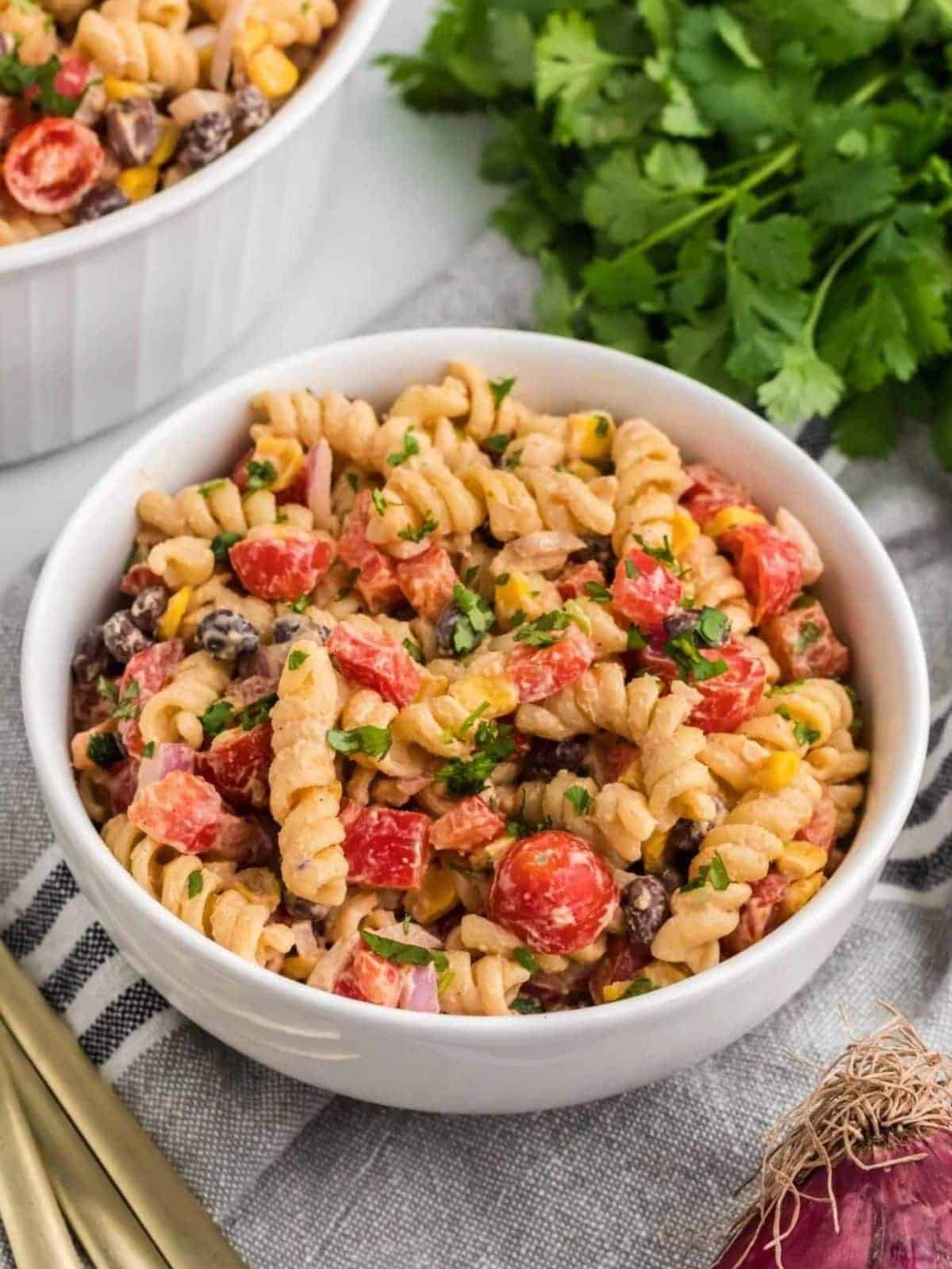 Southwest pasta salad in a white bowl on top of grey striped napkin