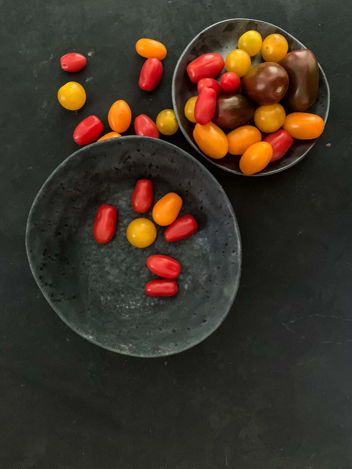 A variety of cherry tomatoes in 2 grey bowls