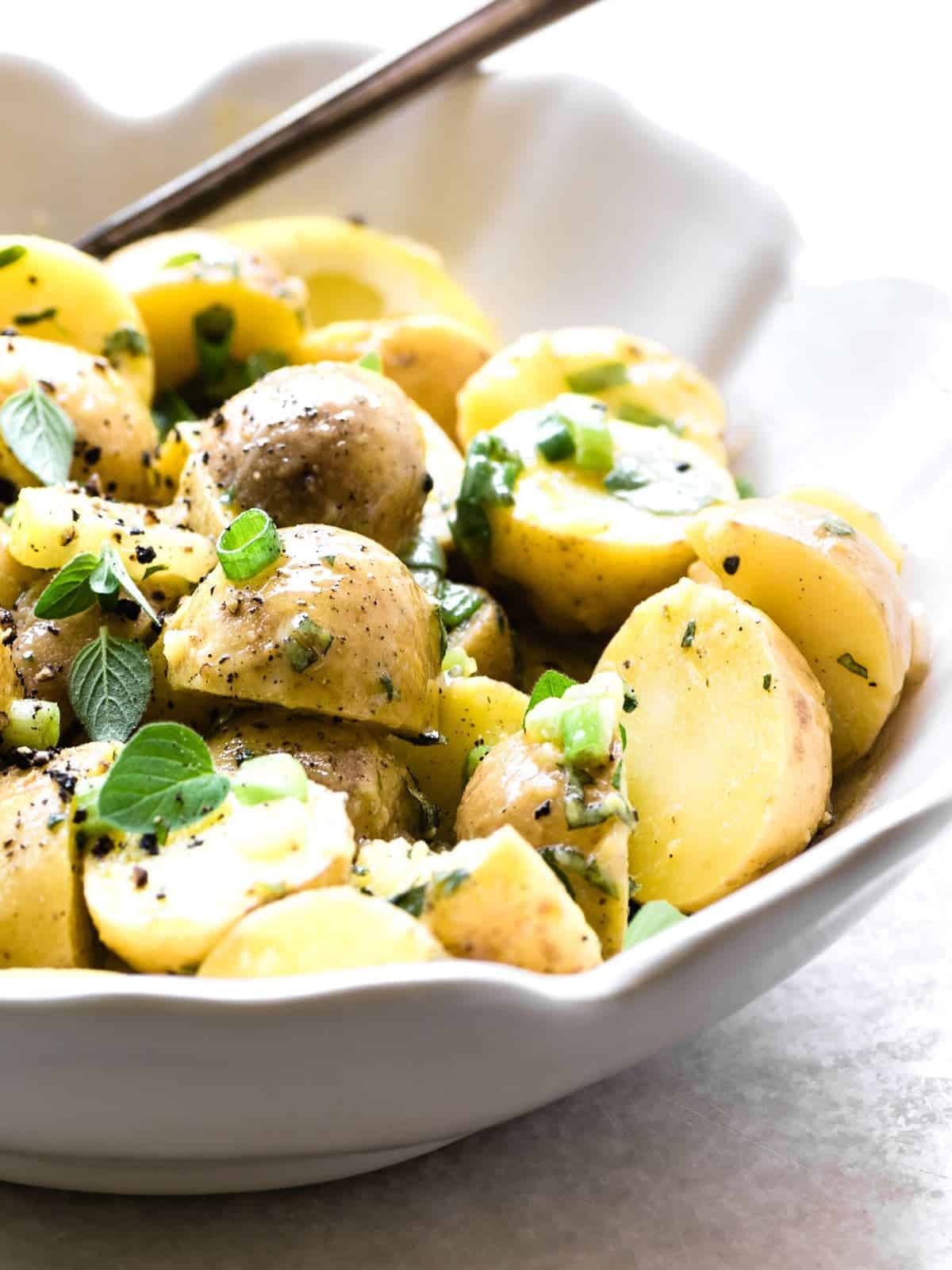 Greek lemon potato salad in a white bowl with a salad server