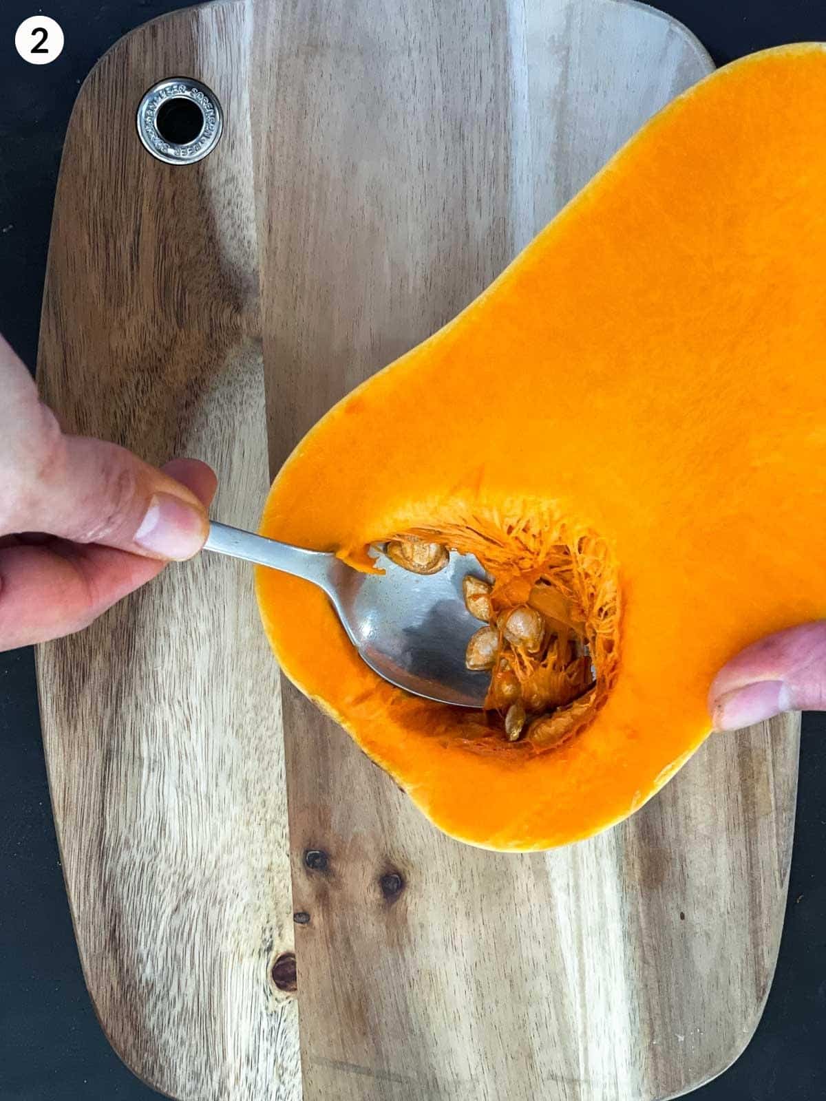 Scooping out seeds form butternut squash with a spoon