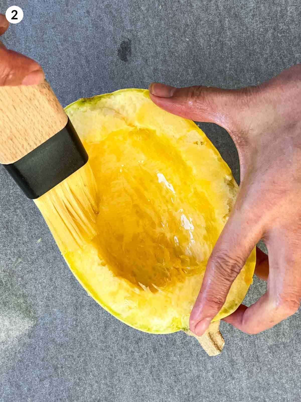 Brushing spaghetti squash half with some olive oil