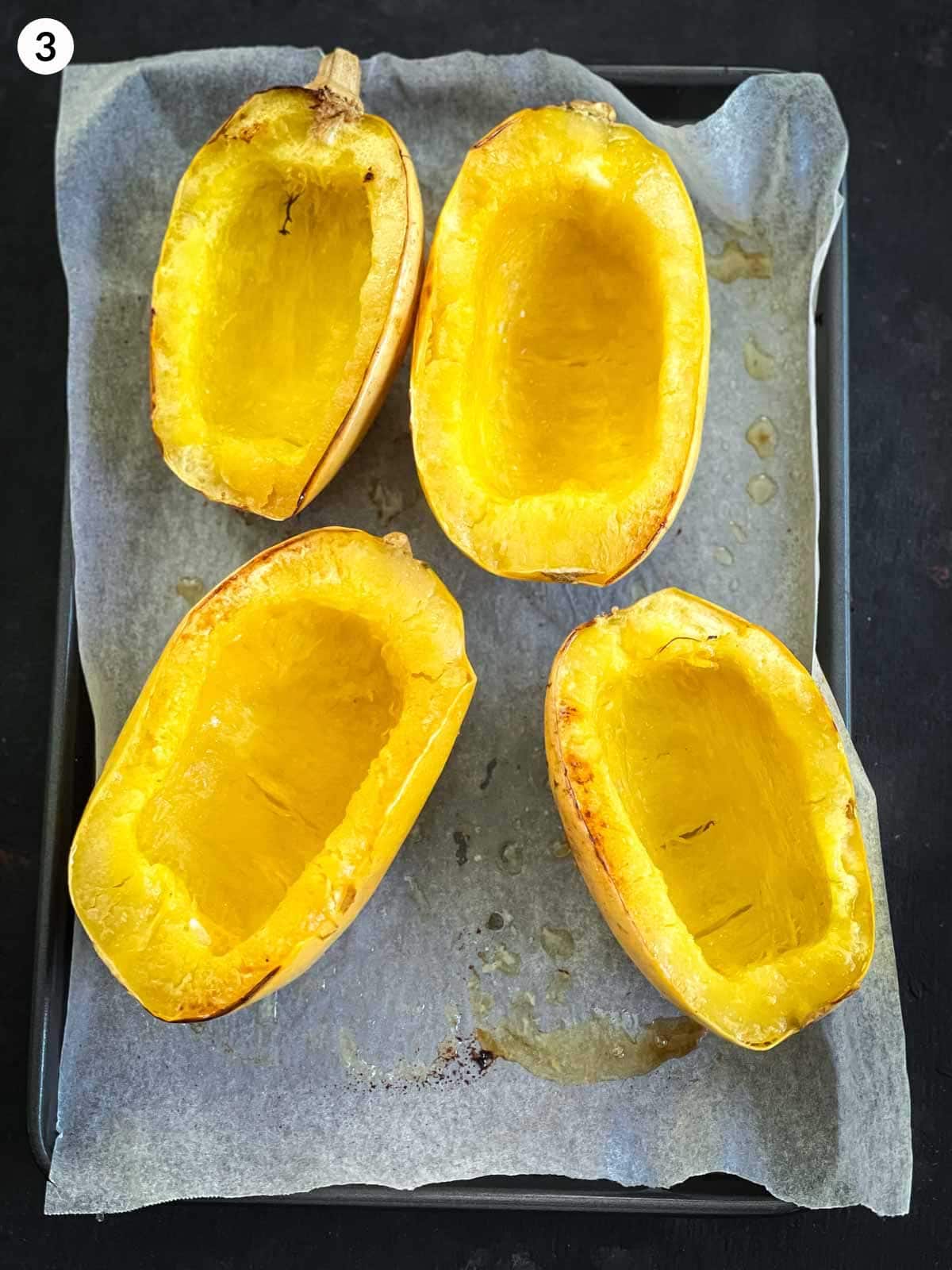 Roasted spaghetti squash flesh with a fork that is on a parchment lined sheet pan
