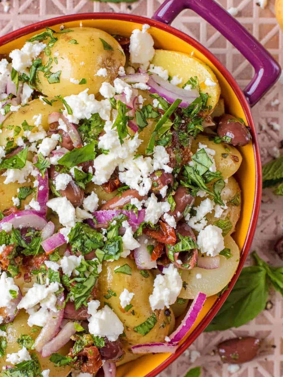 Mediterranean potato salad in a purple and orange casserole dish