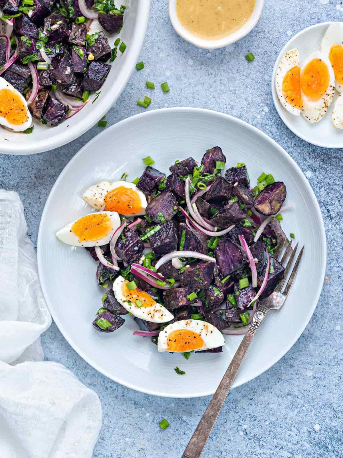 2 serves of purple potato salad with egg on a blue plate
