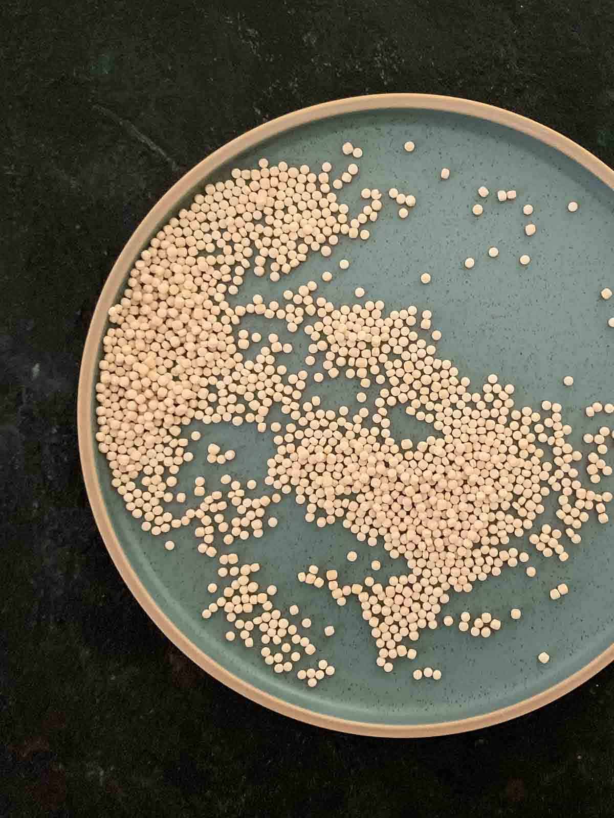 Uncooked pearl couscous on a blue plate