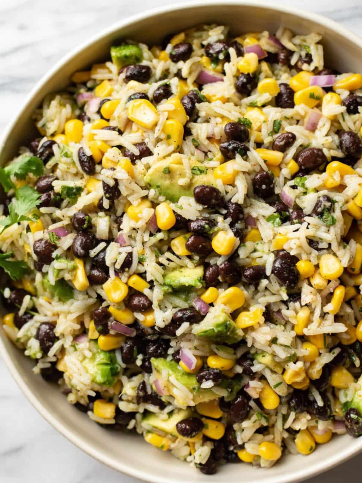 Black bean corn and rice salad in a cream colour bowl on a marble background