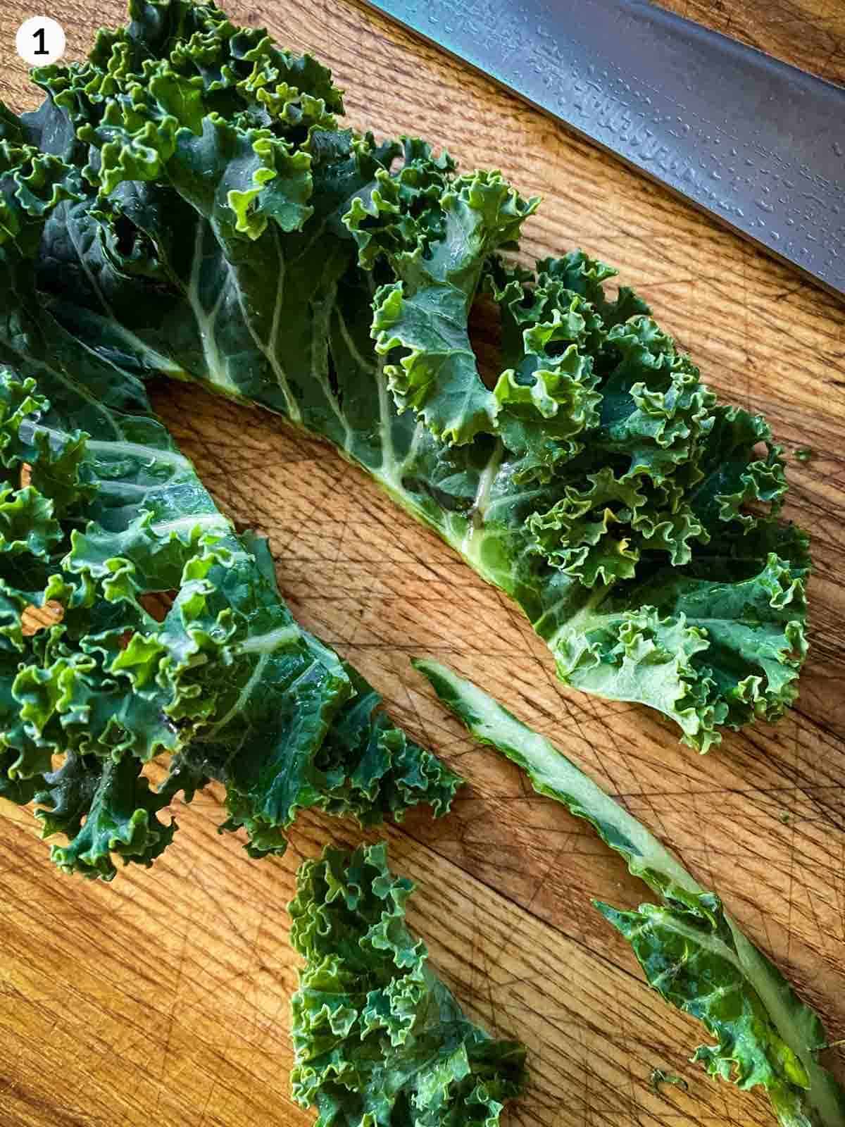 removing the rib from kale on a wooden board