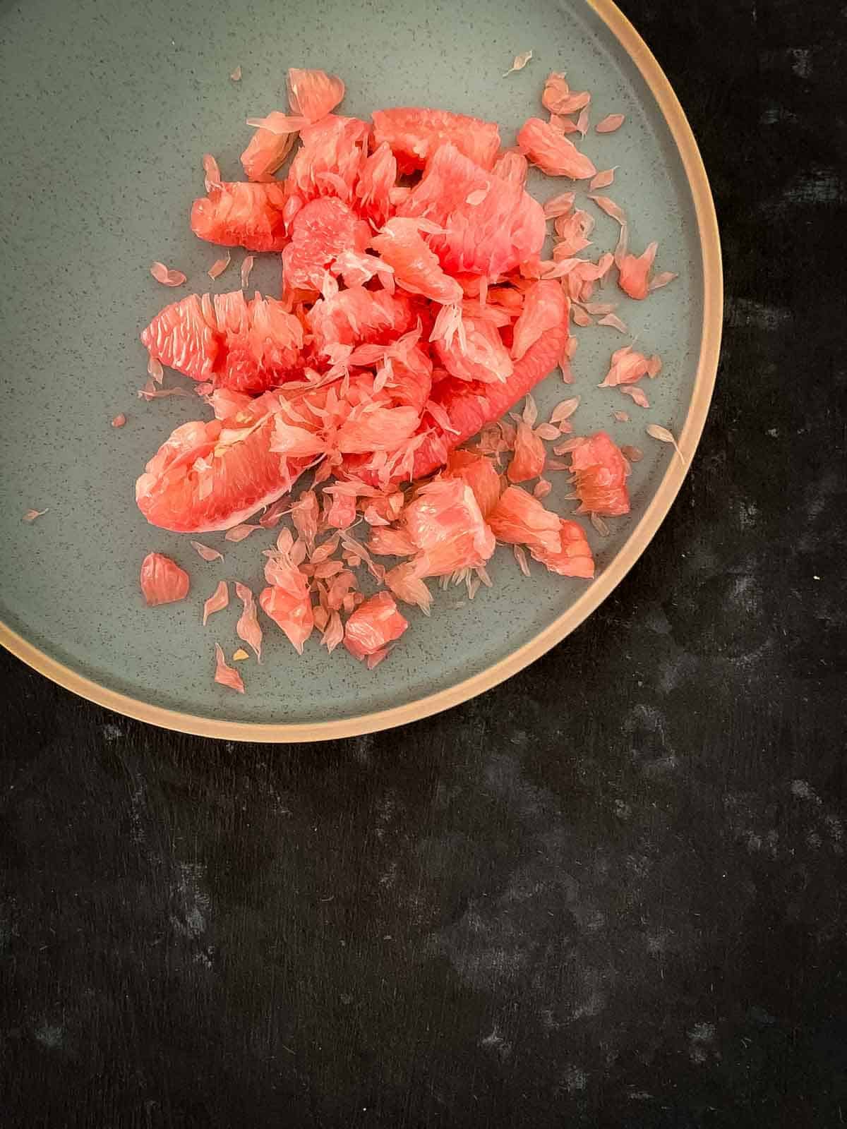 peeled red pomelo flesh on a green plate