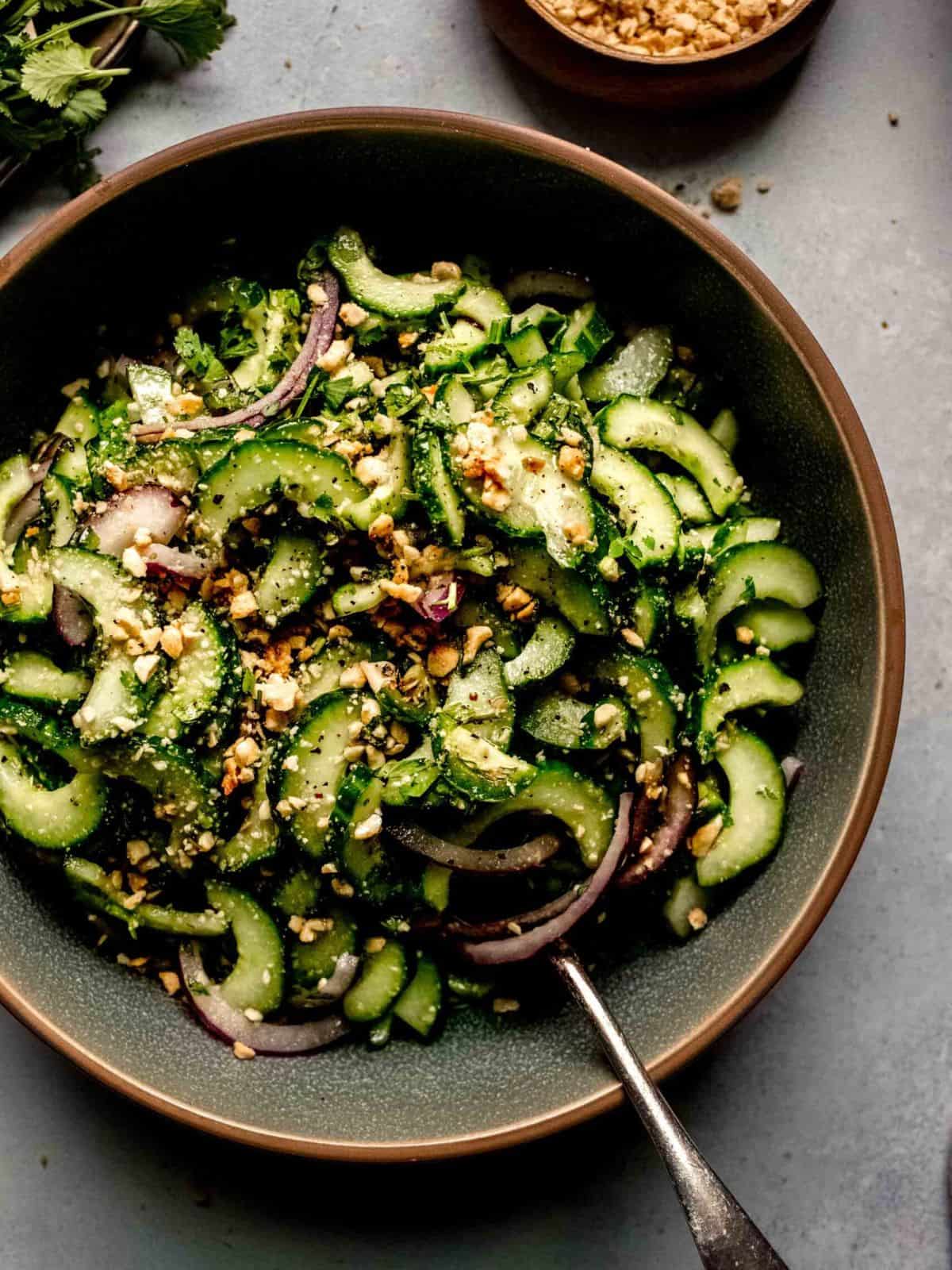 Thai cucumber slaad in a green and brown bowl with a spoon