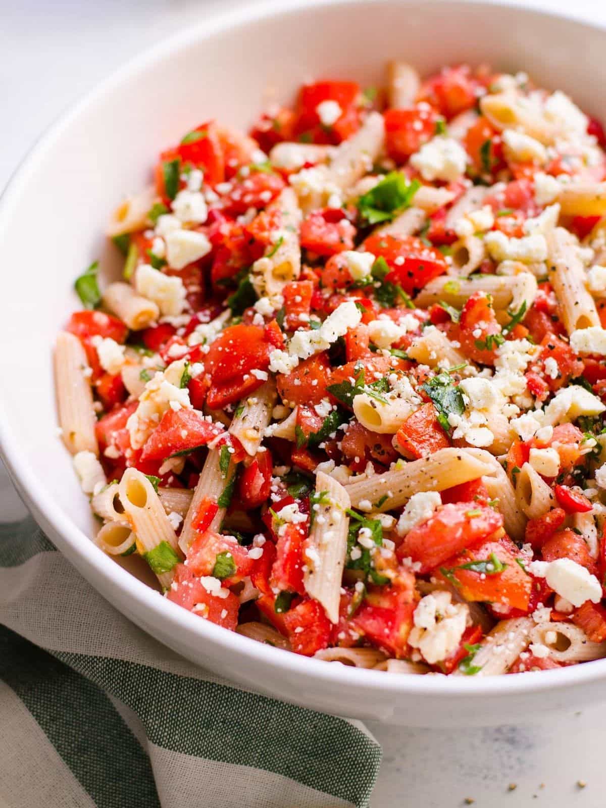 Tomato, basil, feta pasta salad in a white bowl