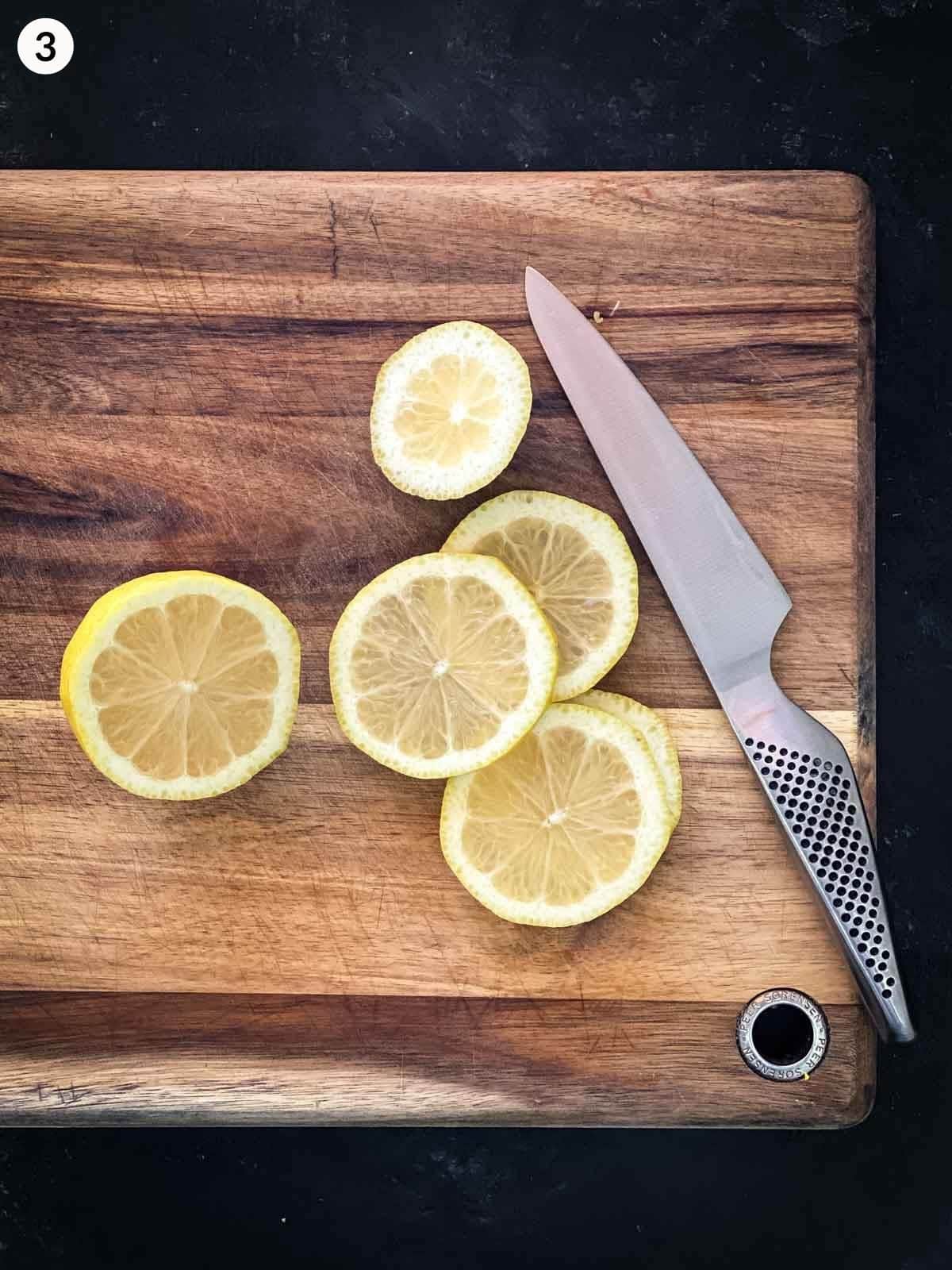slices of lemon cut on a wooden chopping board with knife