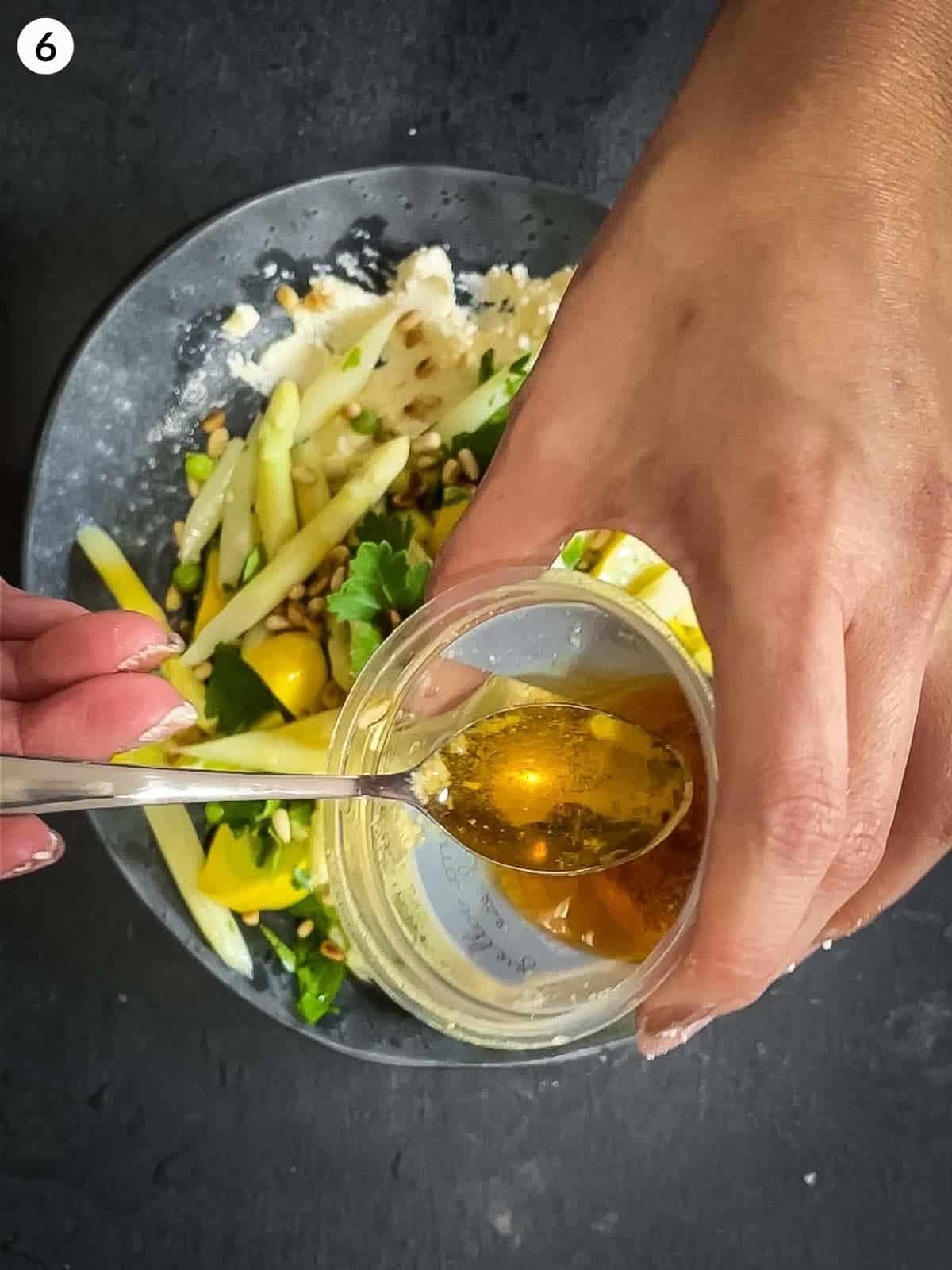 Adding chilli oil on top of white asparagus salad