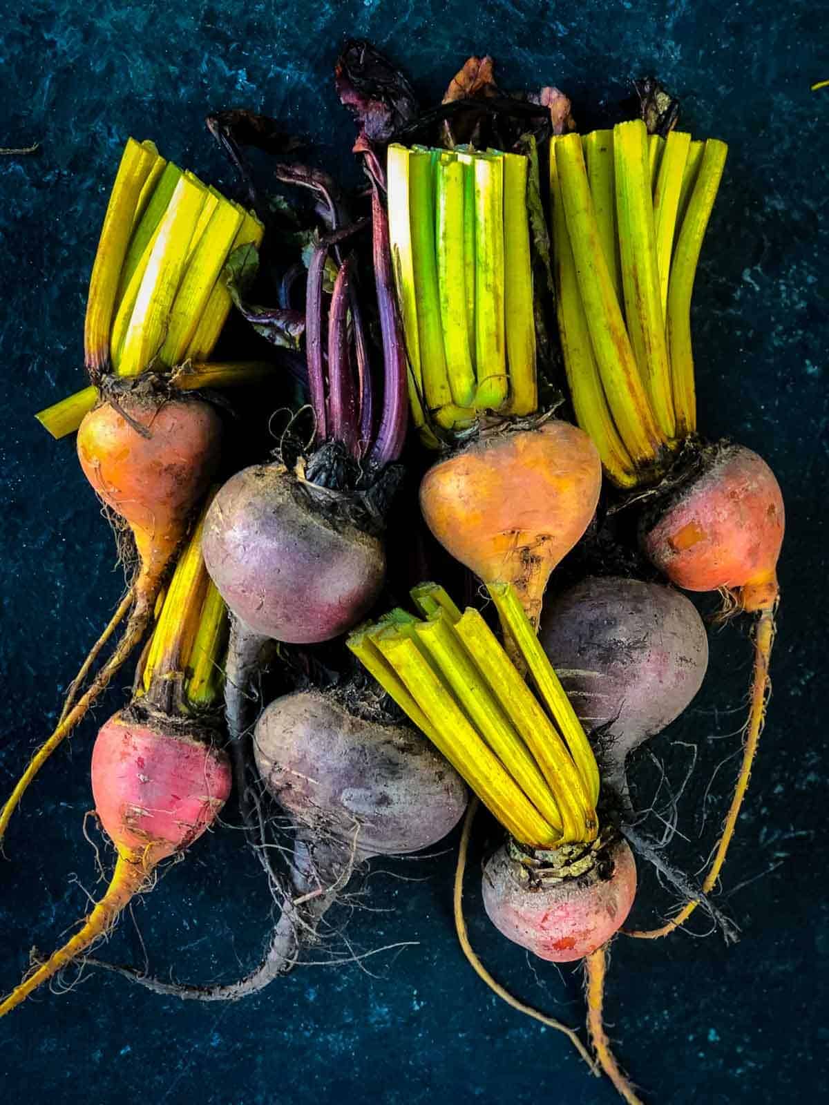 small bunch of coloured baby beet stacked together on a black background