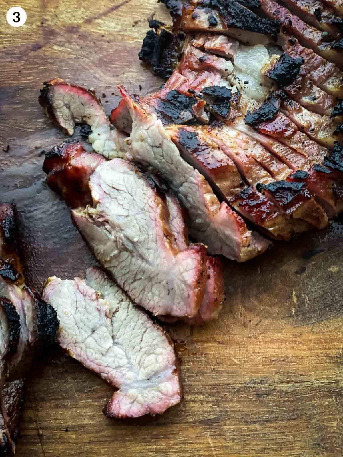 slices of grilled pork cut on a wooden chopping board