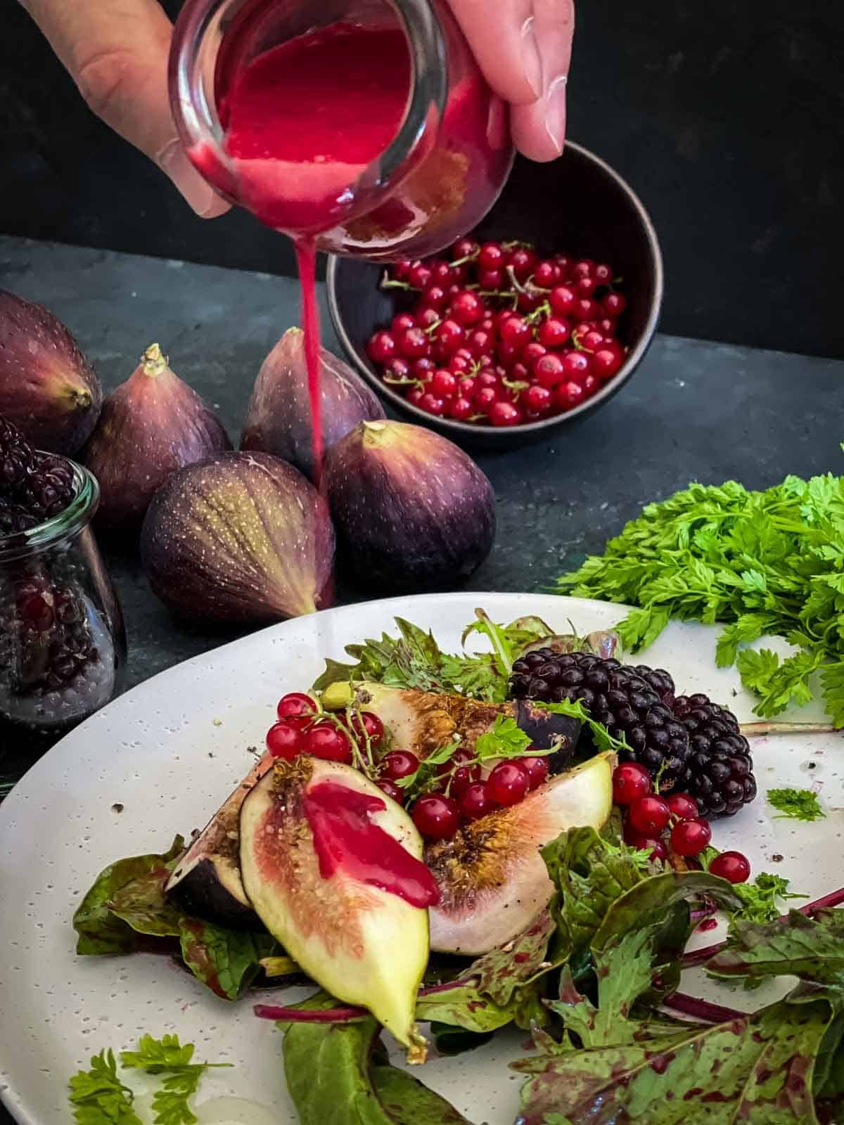 Pouring blackberry salad dressing over red currant salad