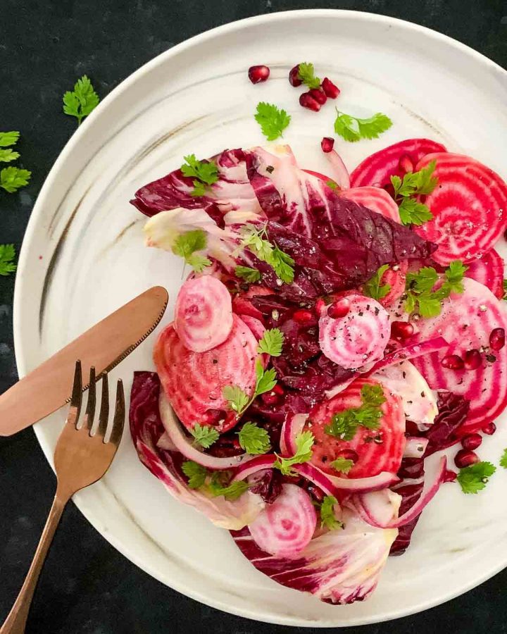 Beetroot Salad with Radicchio and Pomegranate on a white marbled plate with rose gold cutlery