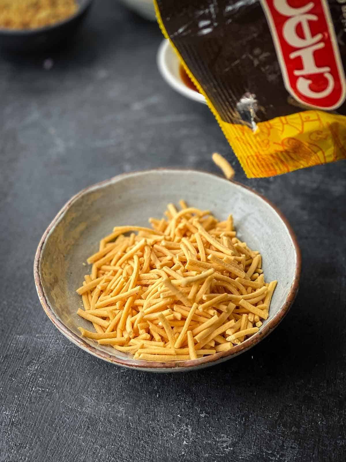 crispy fried noodles being poured out of packet into a small bowl