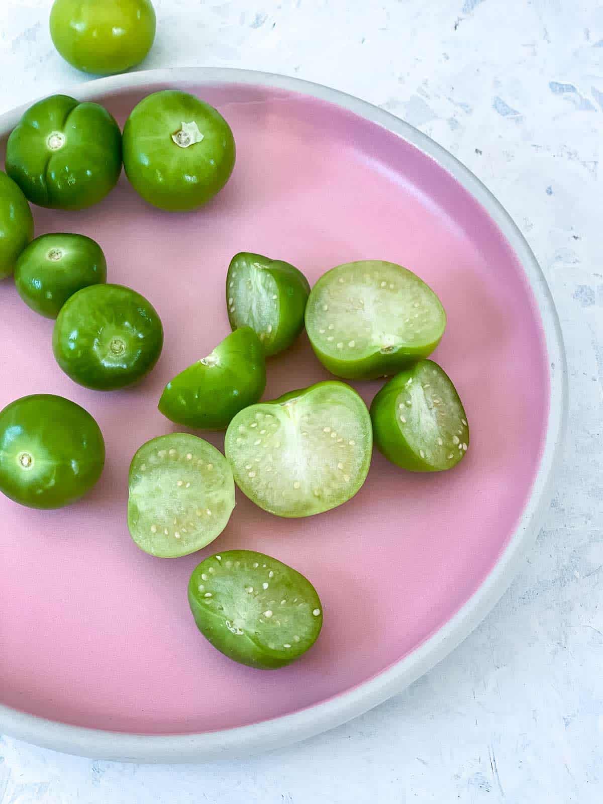 a pink plate of whole and halved tomatillos