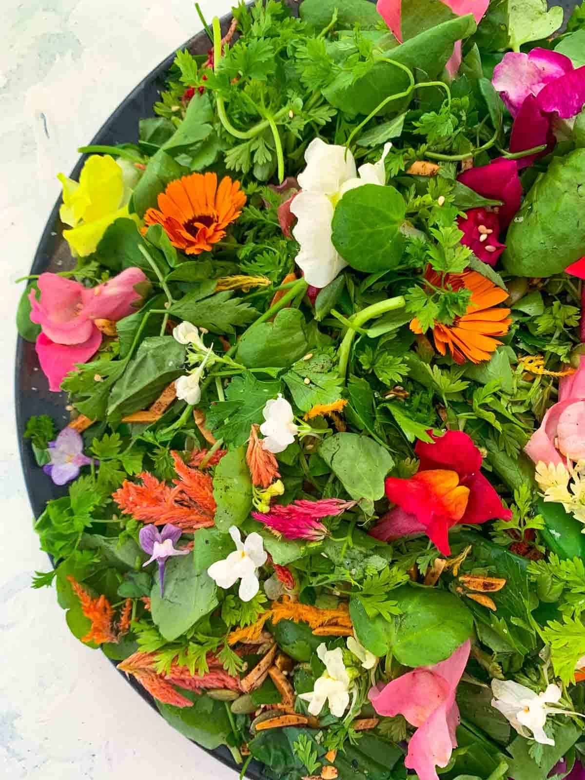 Herb Salad with Edible Flowers on a black platter